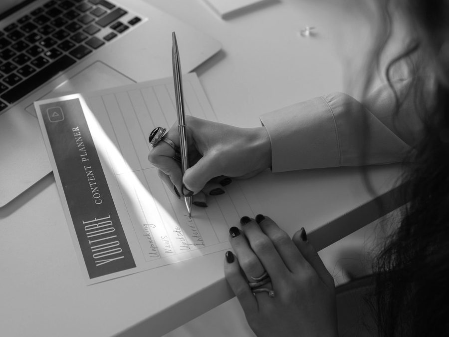 A hand annotating a printed content plan on a desk