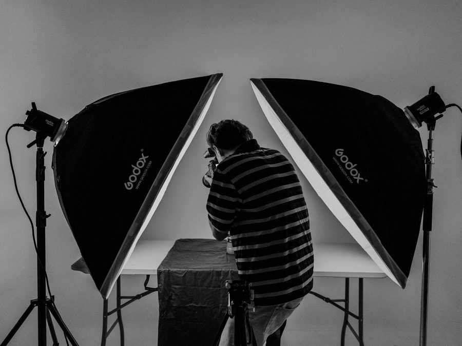 A photographer shooting a product between two studio softboxes