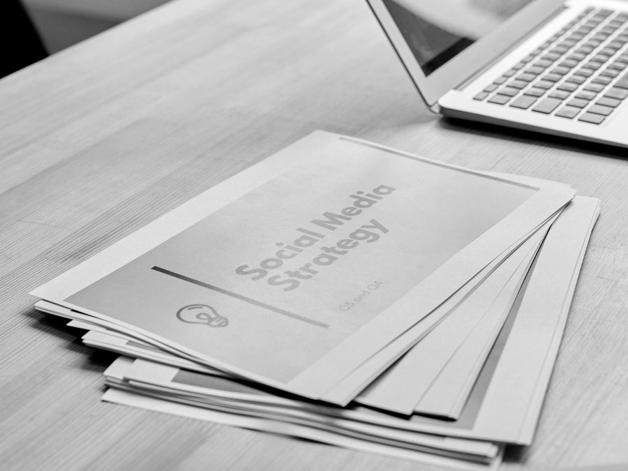 A printed social media strategy document beside a laptop