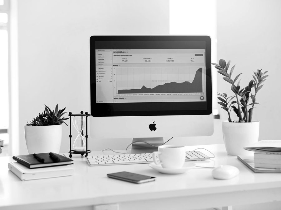 A desktop computer on a clean white desk showing a web analytics chart
